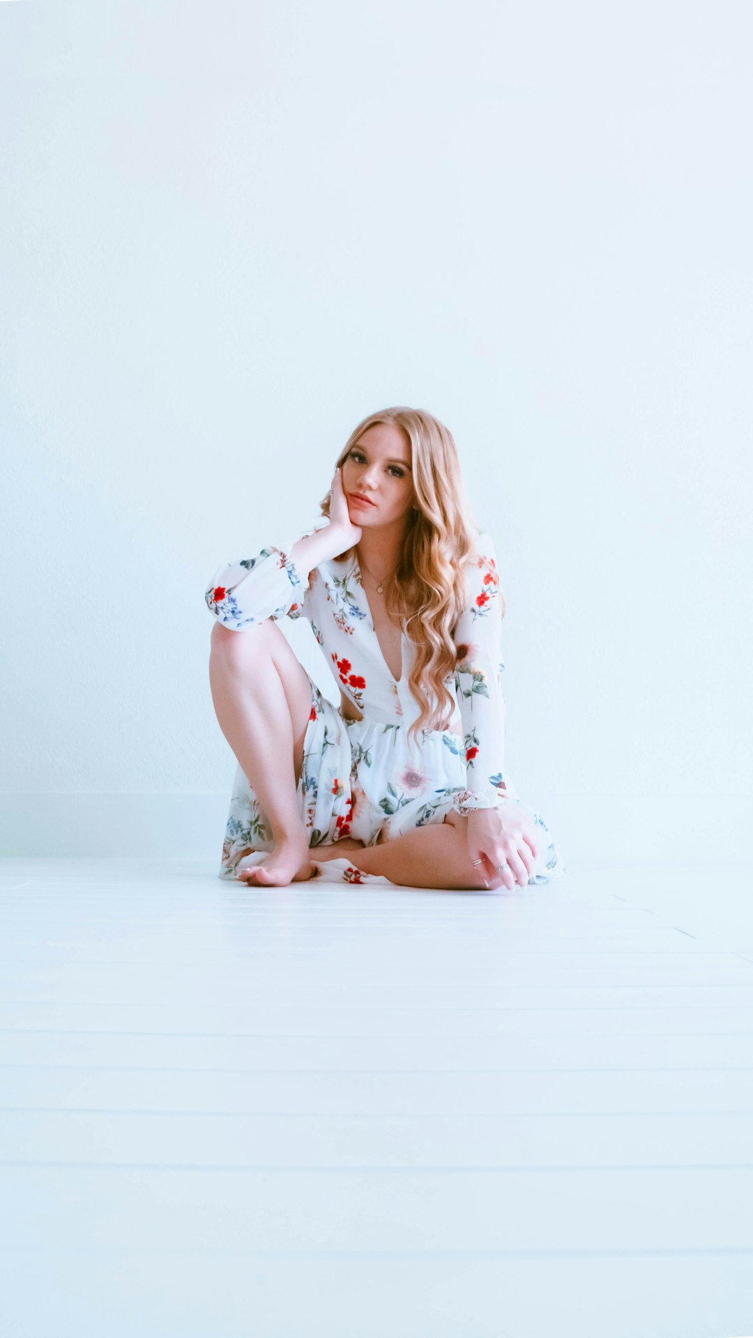 woman in white and red floral dress sitting on white floor