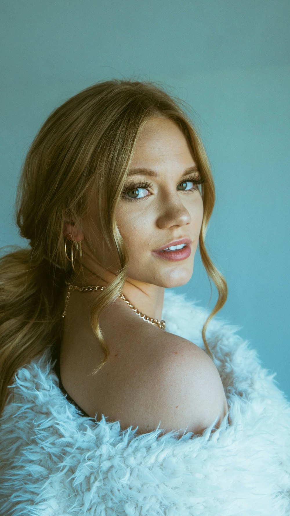 woman in white fur top wearing silver necklace