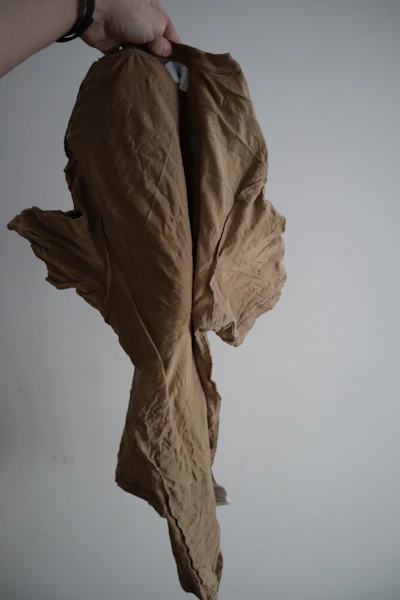 Close-up of hands holding a gently worn, eco-friendly garment with natural textures.