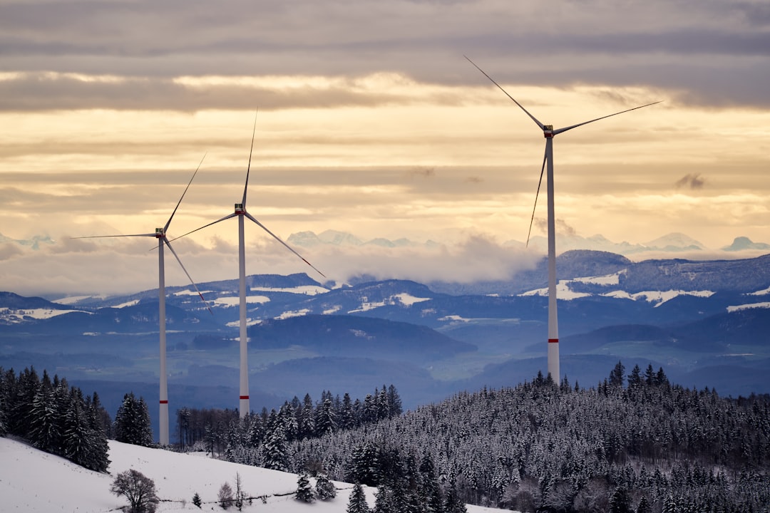 black wind turbines on snow covered mountain during daytime