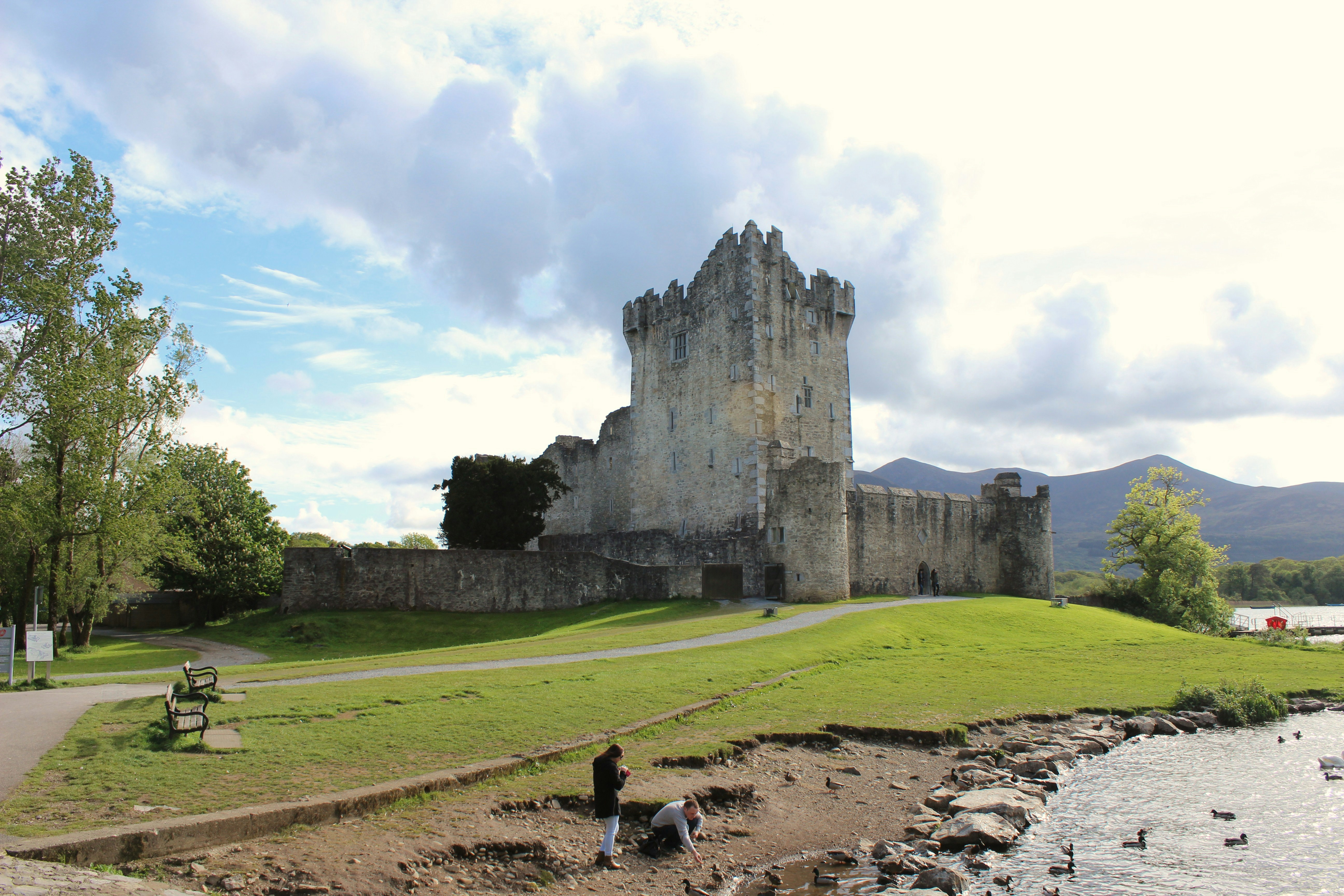woman in black shirt walking on green grass field near gray concrete building during daytime