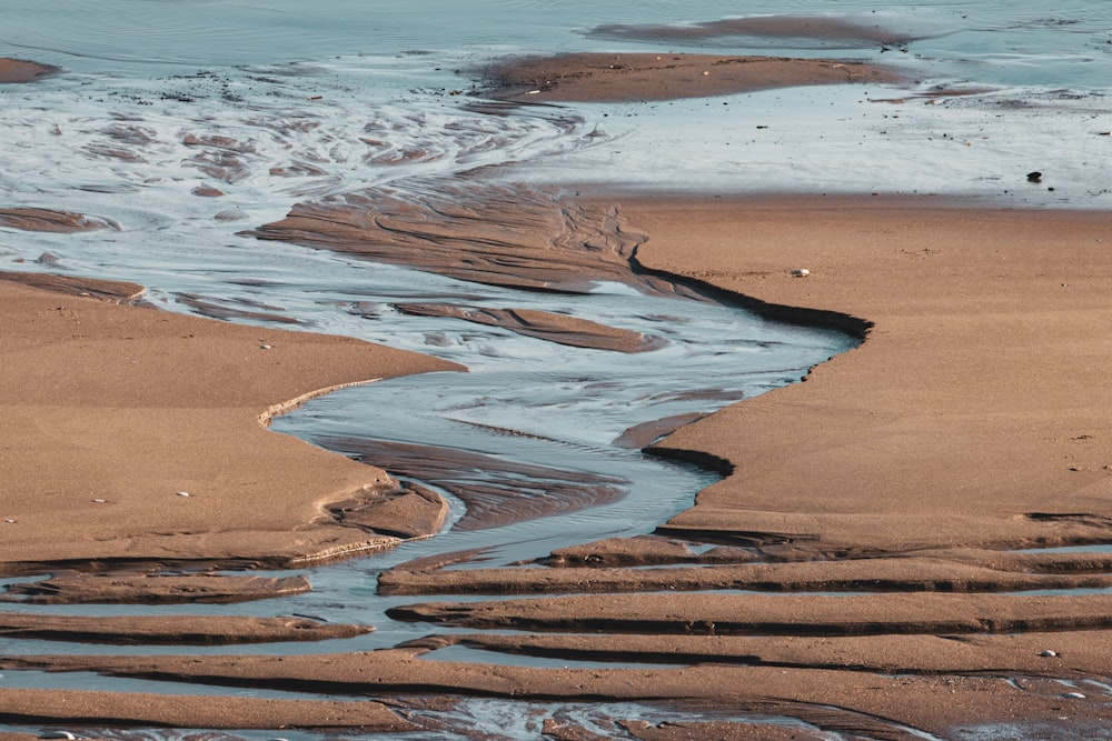 areia marrom perto do corpo de água durante o dia