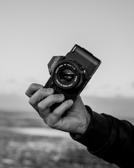 grayscale photo of person holding camera