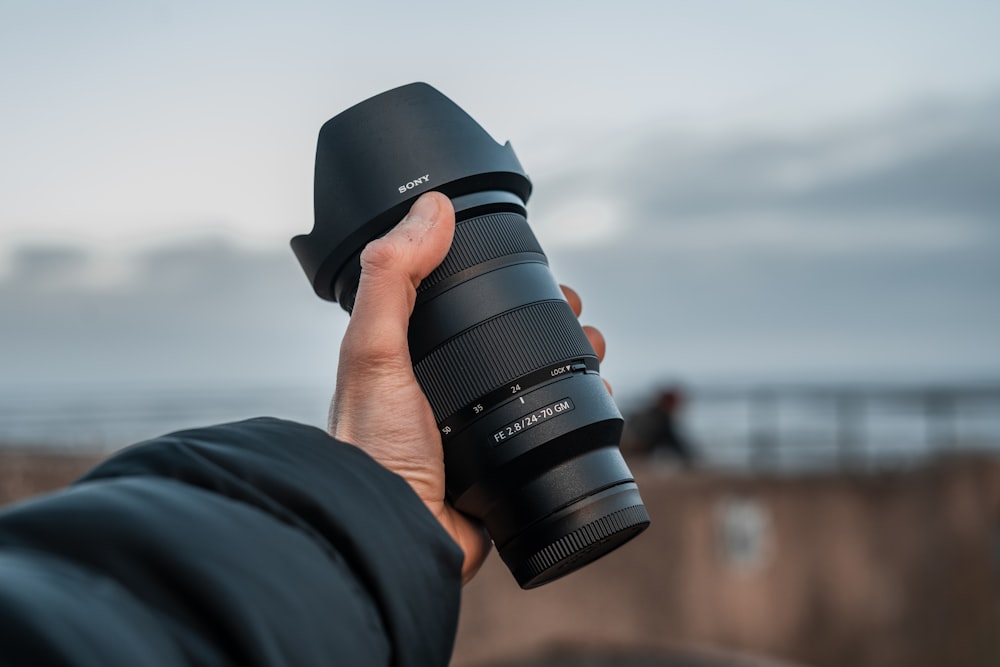 person holding black dslr camera lens