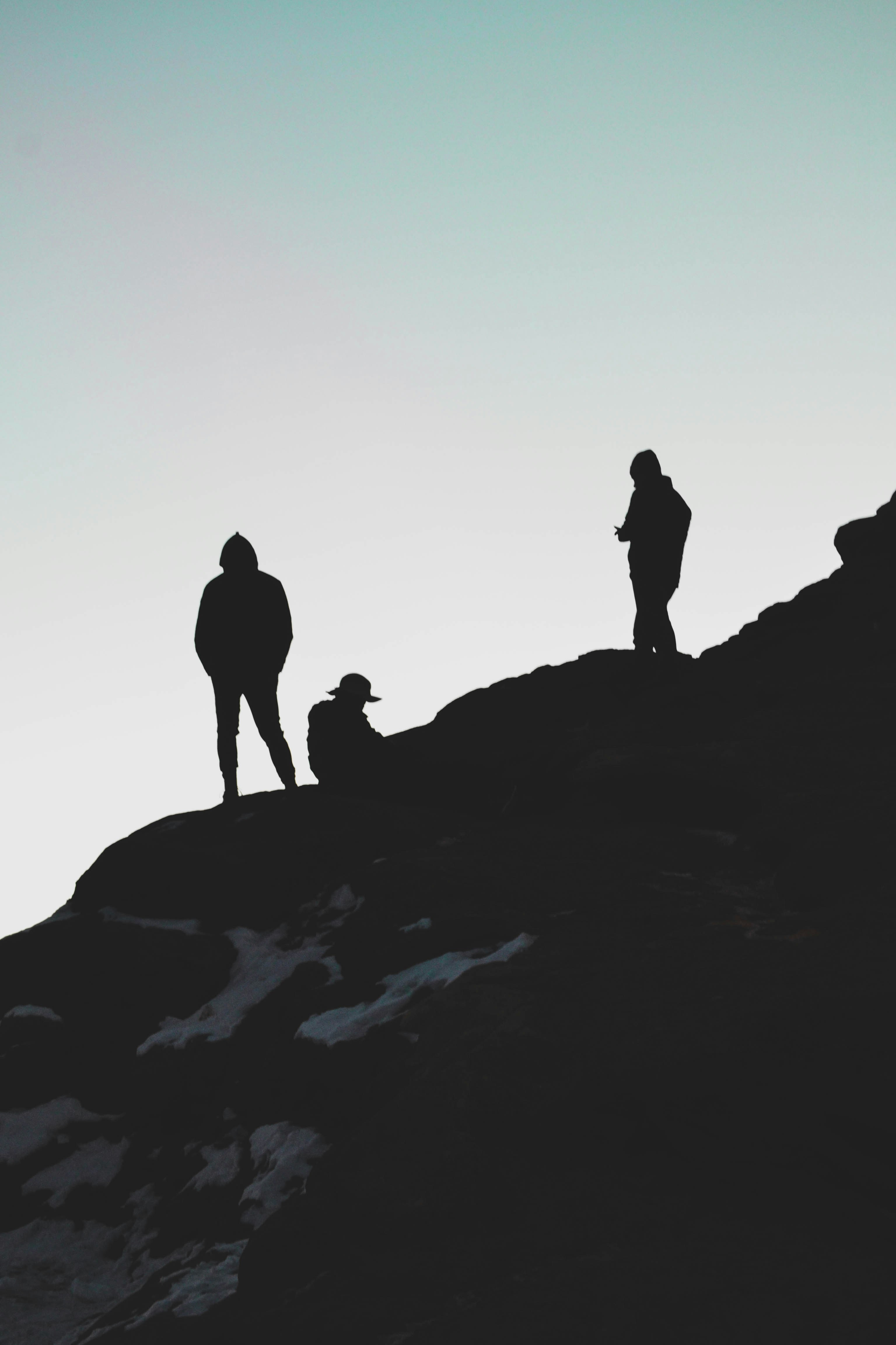 silhouette of 2 people standing on rock formation during sunset