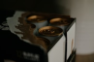 Close-up of the Six Pack Brewing logo embossed on a coffee box in natural daylight.