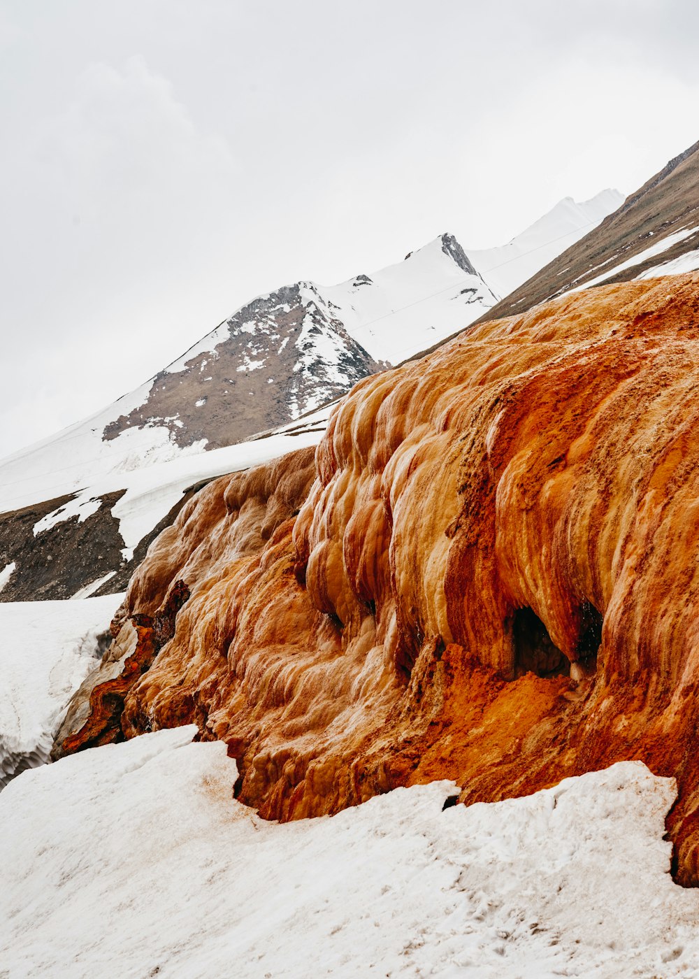 brown rocky mountain covered by snow during daytime