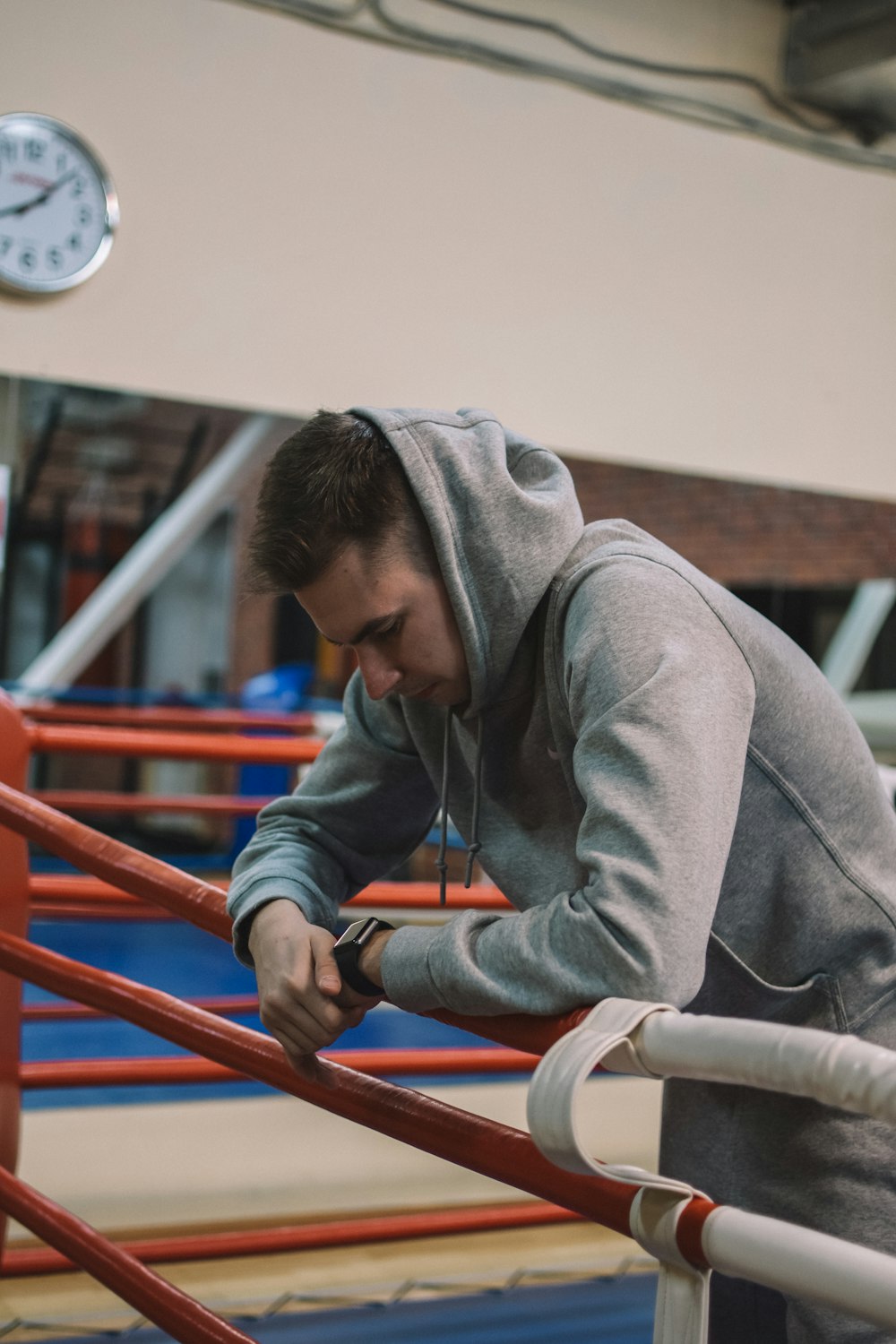 man in gray hoodie and black pants sitting on red metal railings during daytime