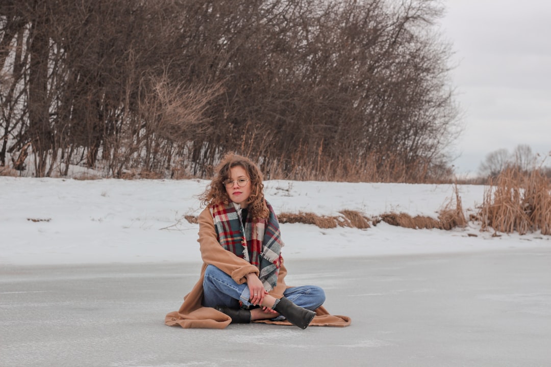 woman in blue denim jeans sitting on snow covered ground during daytime