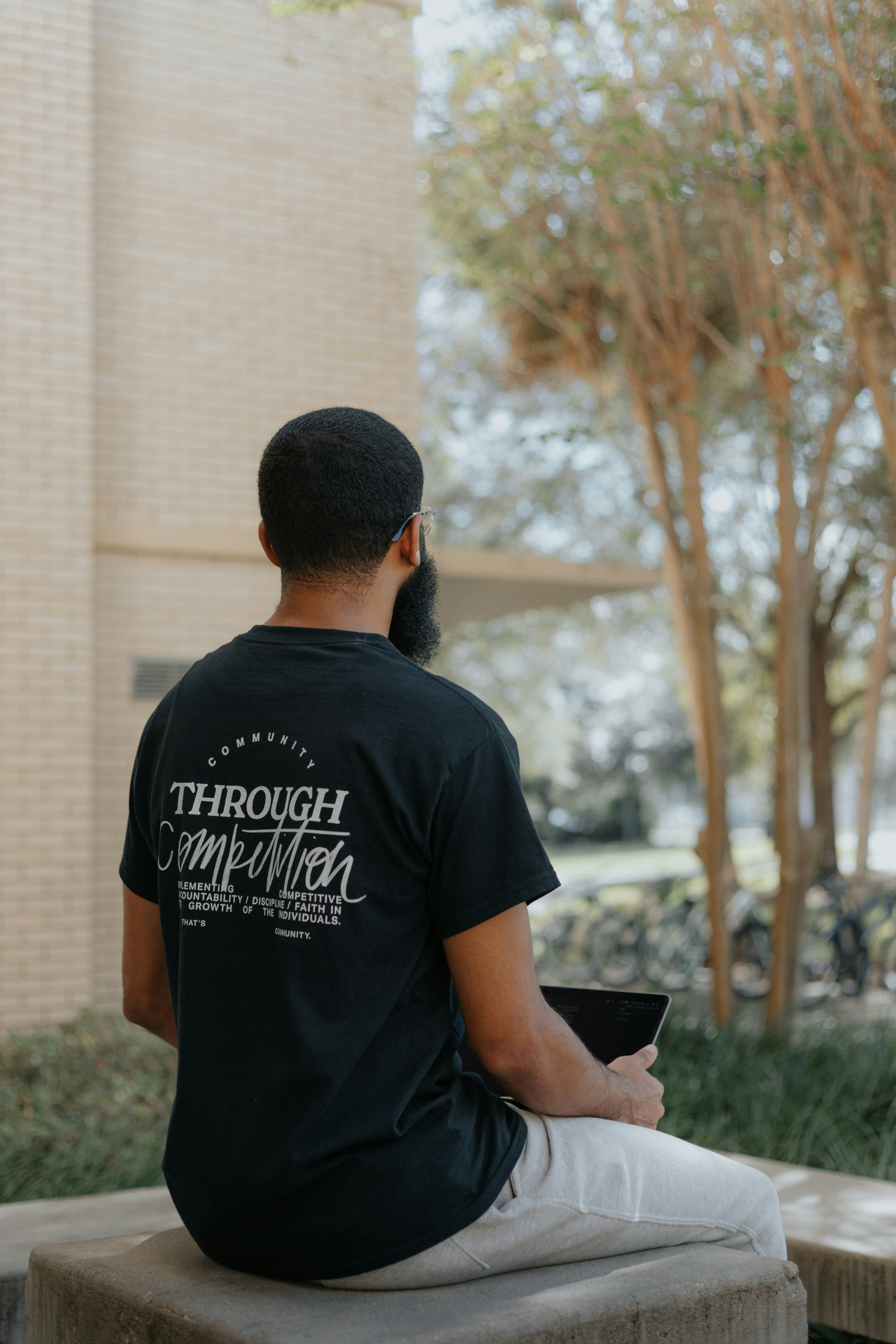 man in black crew neck t-shirt standing near brown concrete building during daytime