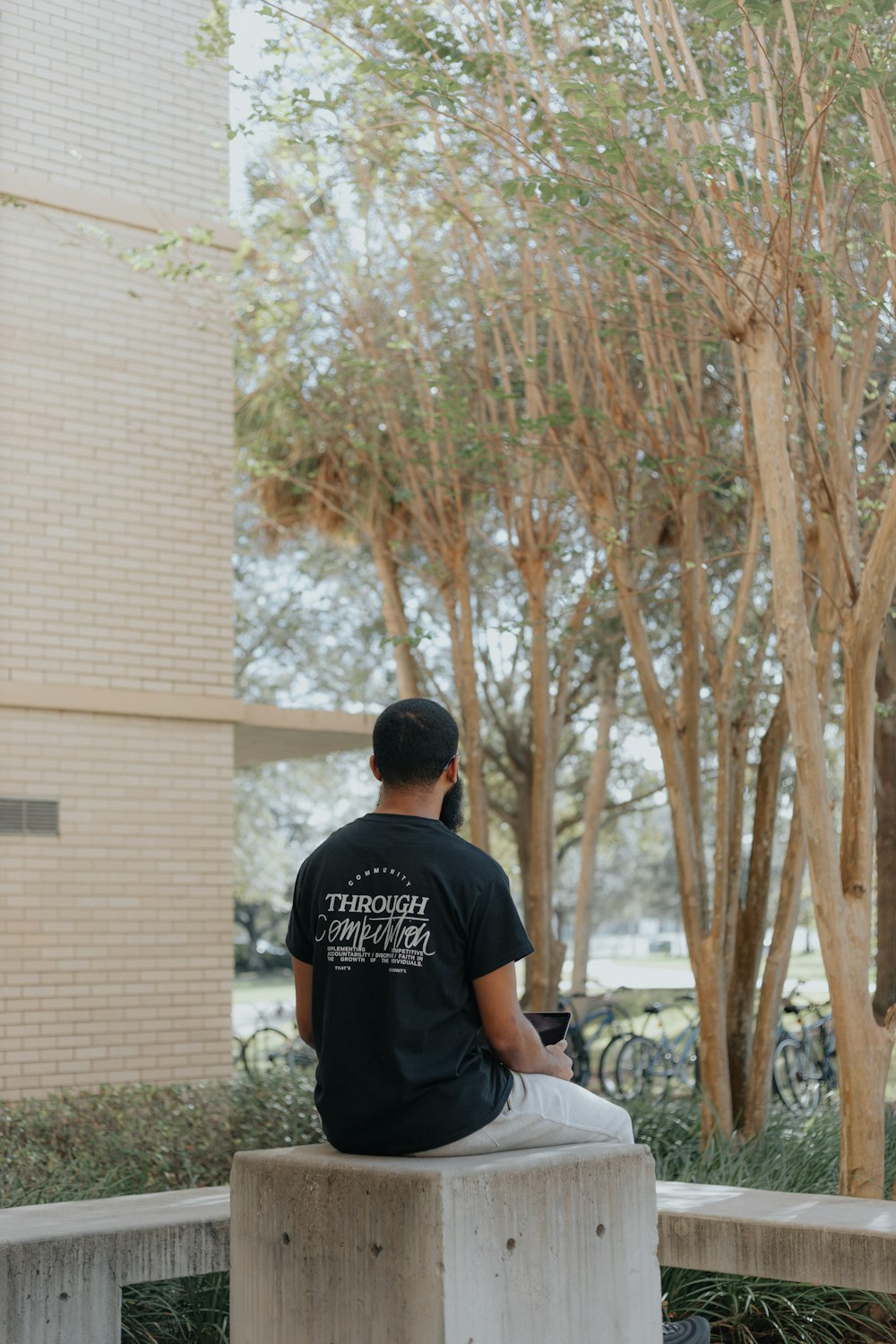 man in black crew neck t-shirt standing near brown tree during daytime