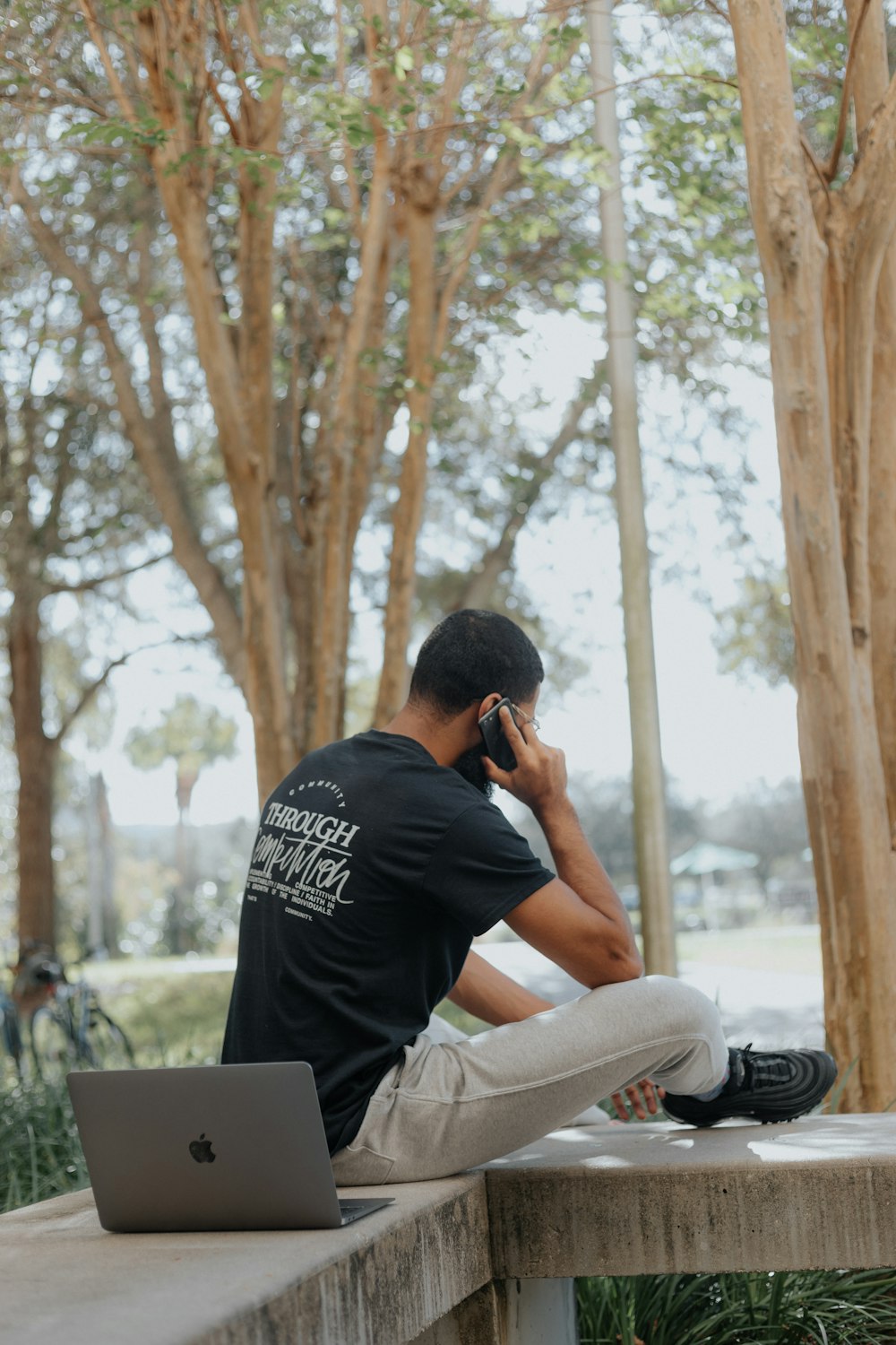 man in black t-shirt and gray pants sitting on brown wooden bench