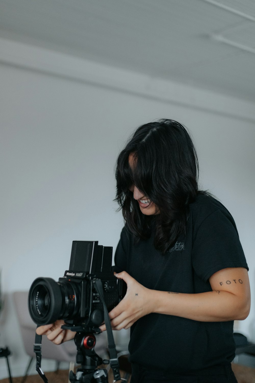 黒いデジタル一眼レフカメラを持つ黒いTシャツの女性