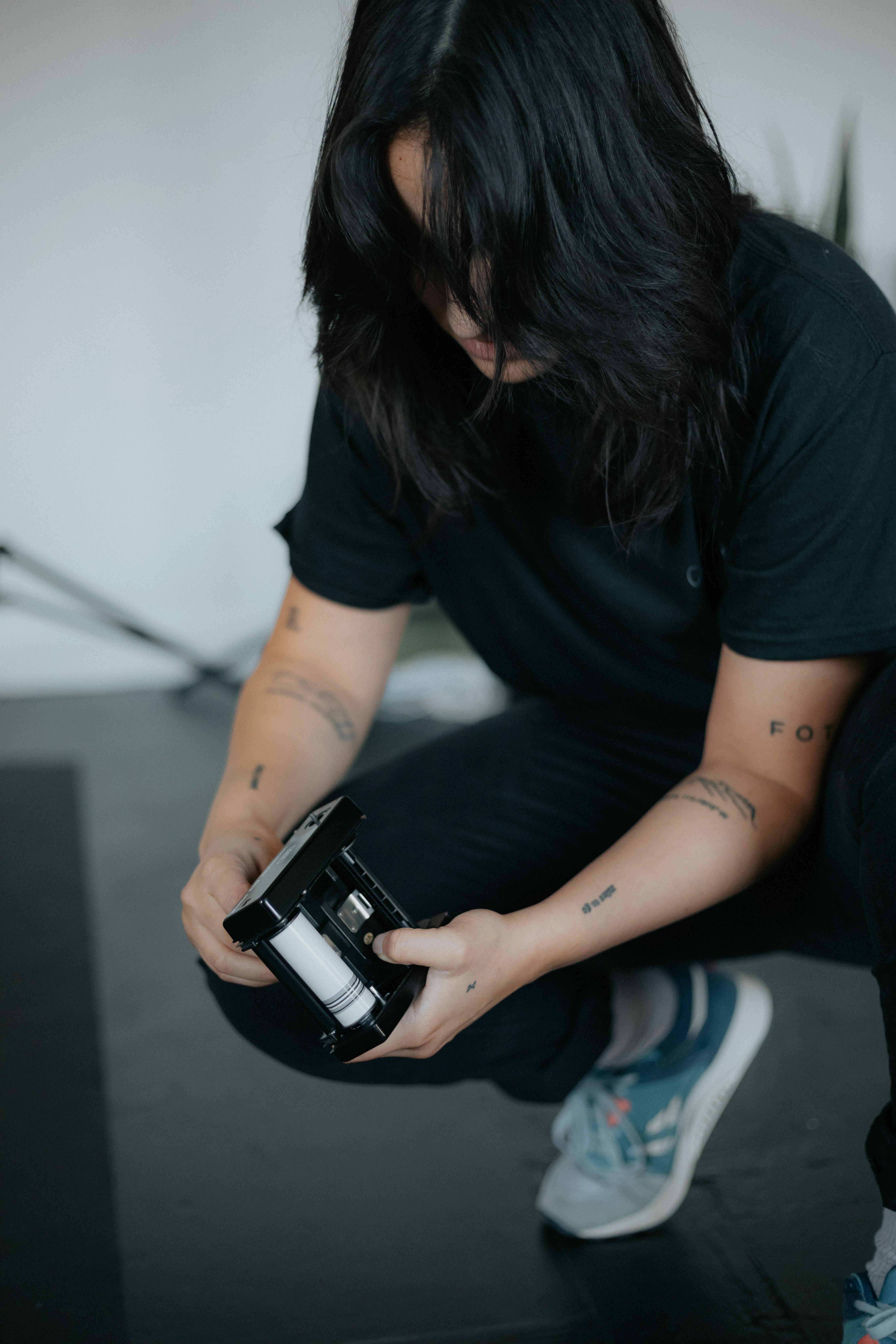 man in black t-shirt and blue denim jeans holding black dslr camera
