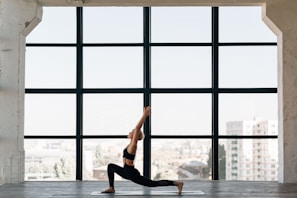 Woman practicing yoga on a mat near a sunny window with plants