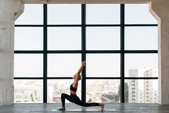 A professional practicing yoga during a work break in a modern office space with calming natural light.