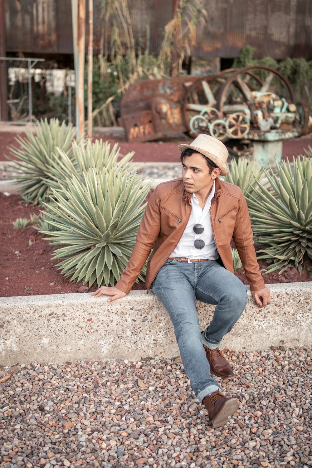 woman in brown jacket and blue denim jeans sitting on concrete floor