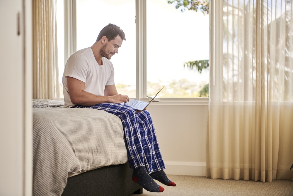 man in white t-shirt sitting on bed