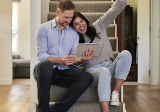 woman celebrating besides man looking at tablet