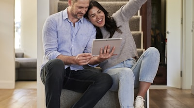 woman celebrating besides man looking at tablet
