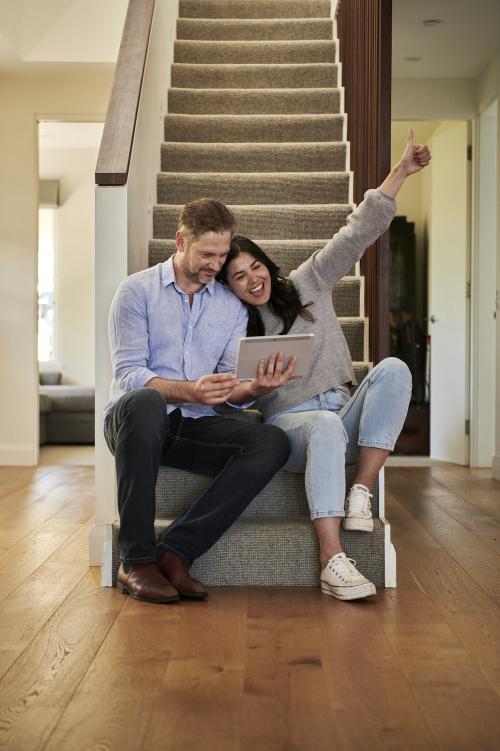 woman celebrating besides man looking at tablet