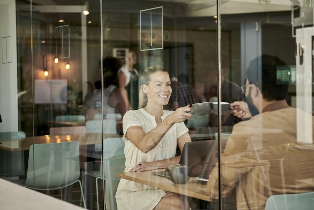 woman in white shirt sitting at coffee shop with man in brown jacket