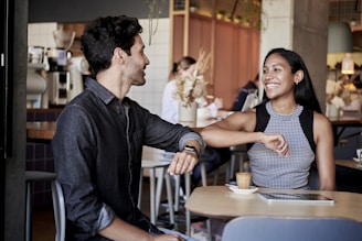 man in black shirt elbow bumping with woman in a restaurant