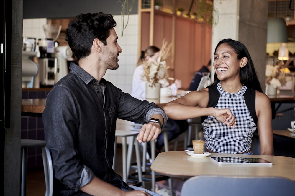 man in black shirt elbow bumping with woman in a restaurant