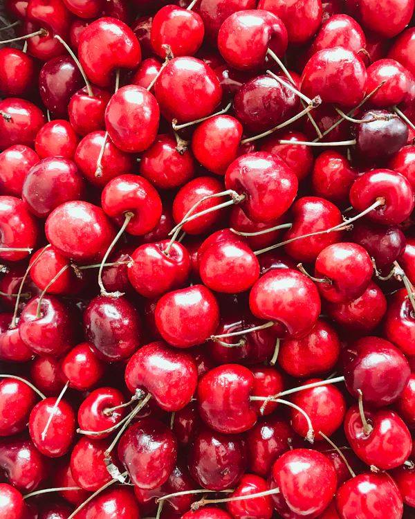 Cerises rouges juteuses en gros plan — les notes de tête cerise et framboise de Nina Rouge Crush de Nina Ricci chez Olara