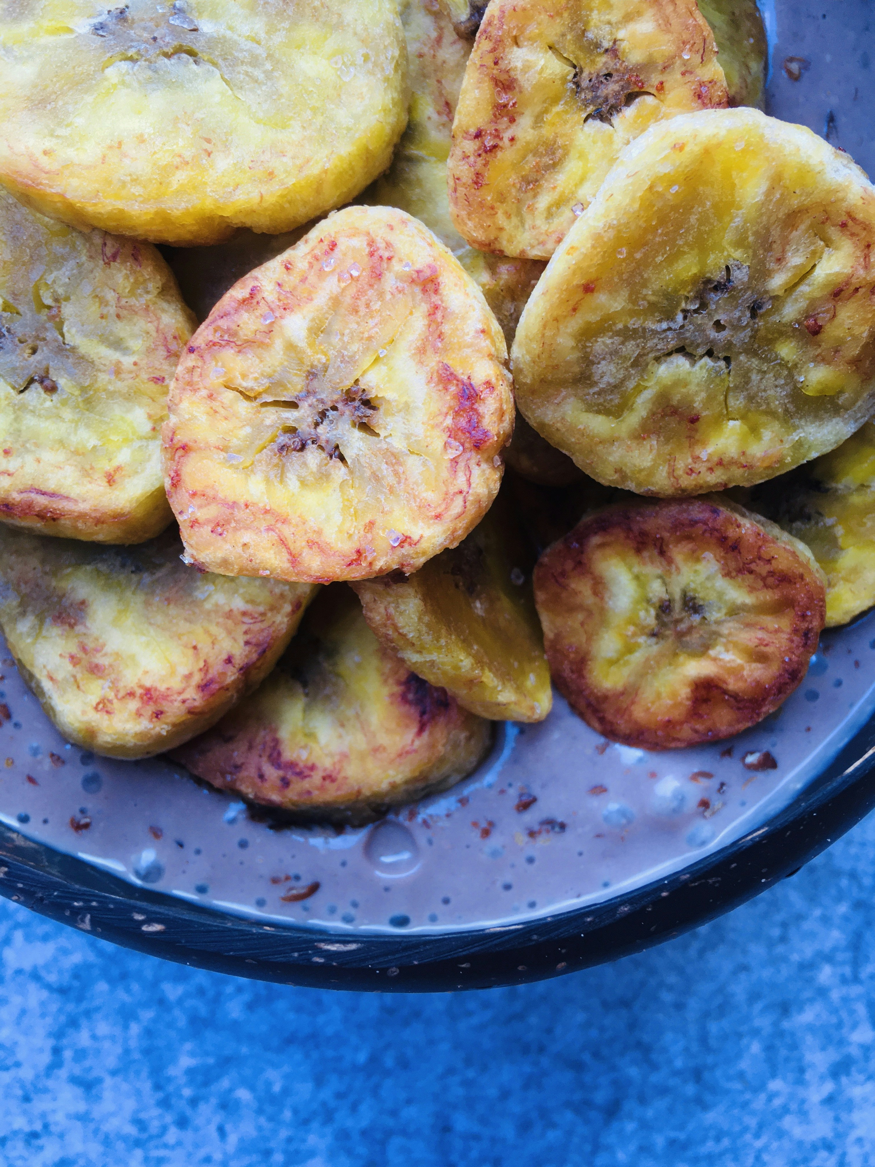 Golden fried plantain slices arranged beside a bowl of brown beans stew, vibrant yellow and brown tones