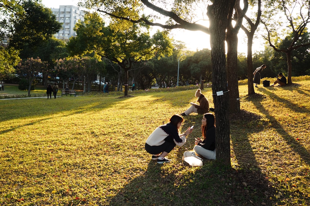 woman in black shirt and black pants sitting on green grass field near trees during daytime