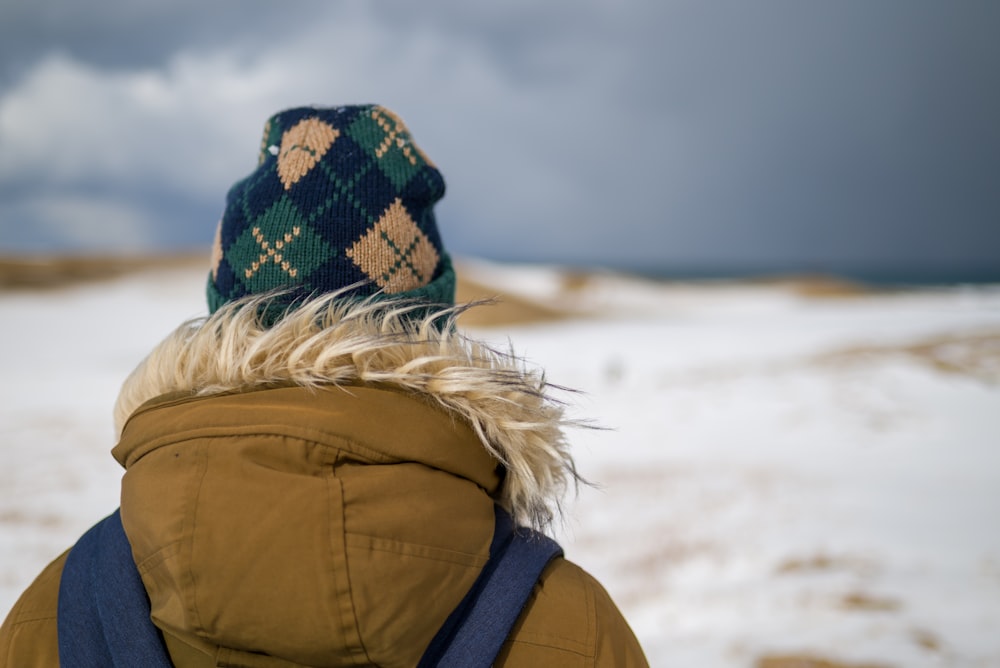 person in brown jacket and black and white knit cap