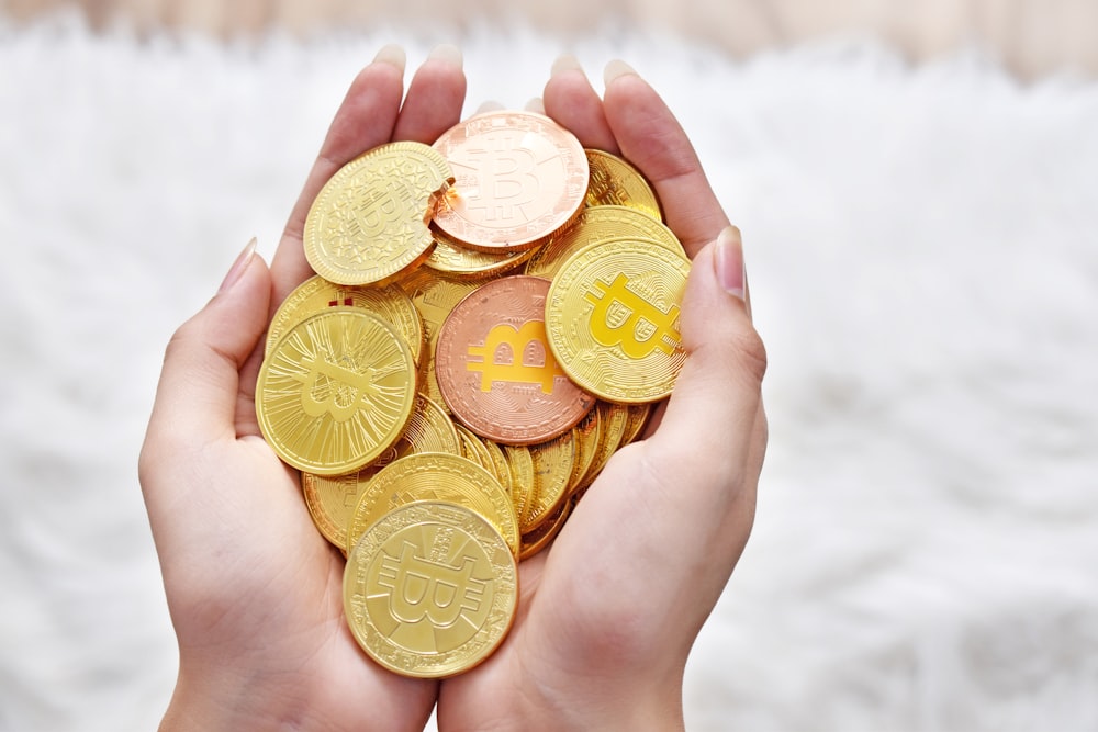 person holding gold round coins