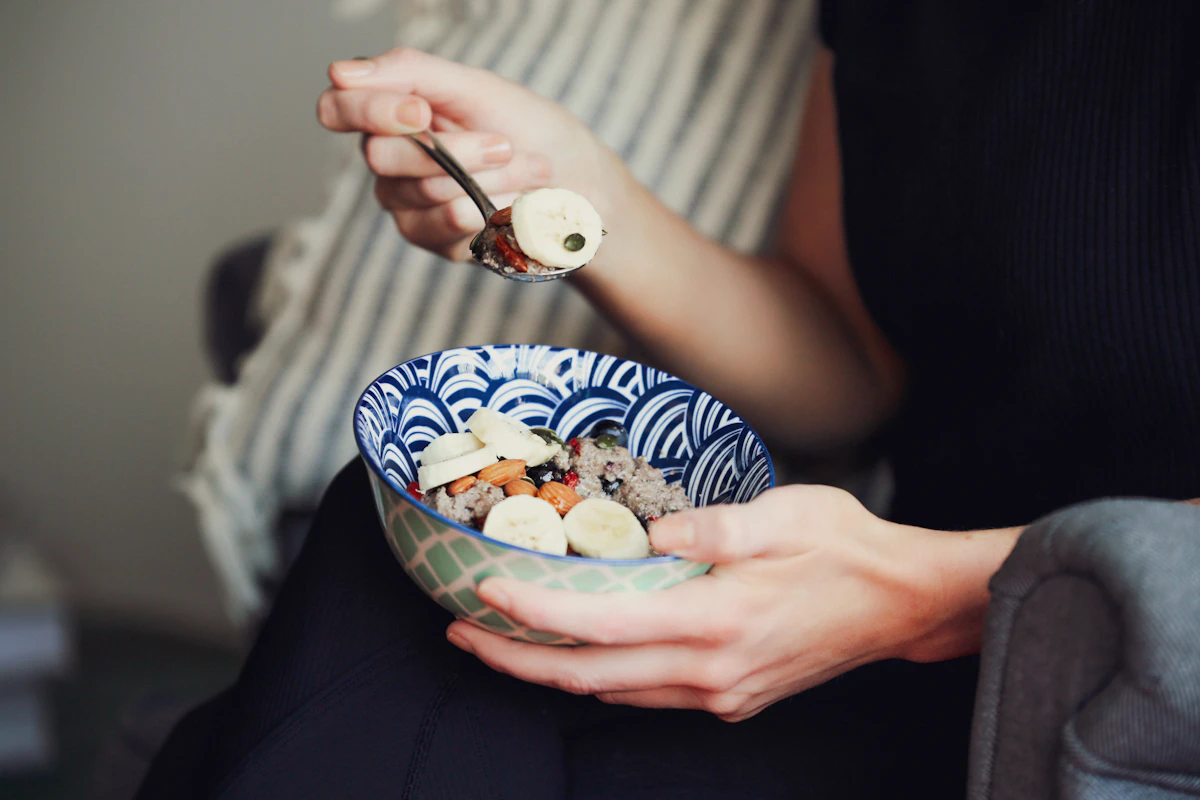 A hand holding a spoon over a bowl of food