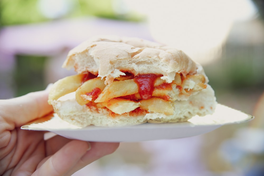 personne tenant un hamburger avec de la tomate et du fromage