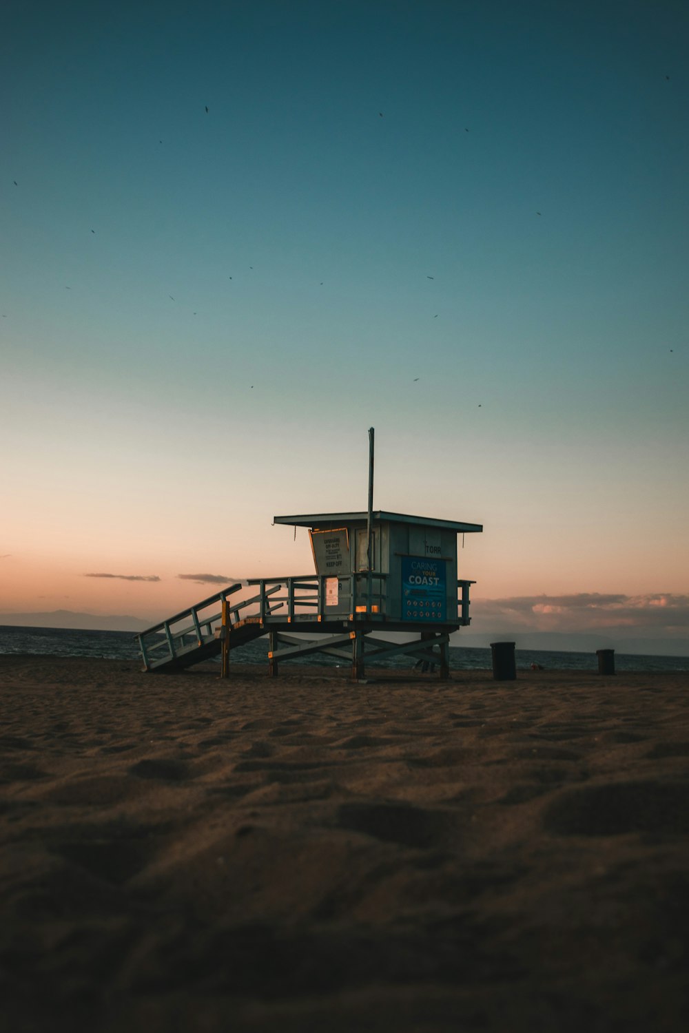 Casa de salvavidas azul en la playa durante la puesta de sol