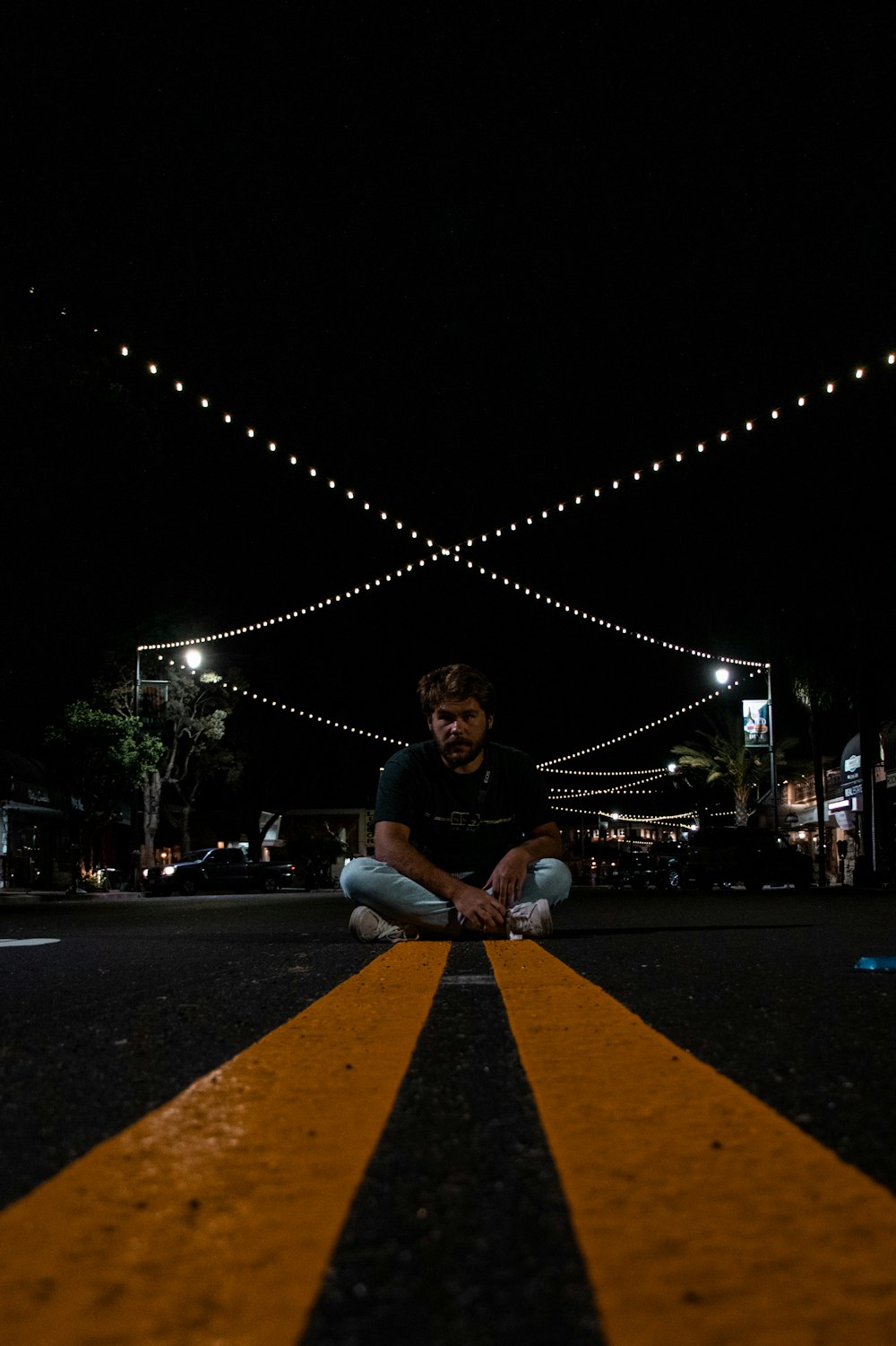 woman in blue long sleeve shirt sitting on the road during night time