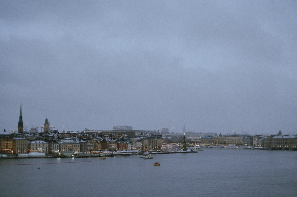 body of water near city buildings under white cloudy sky during daytime