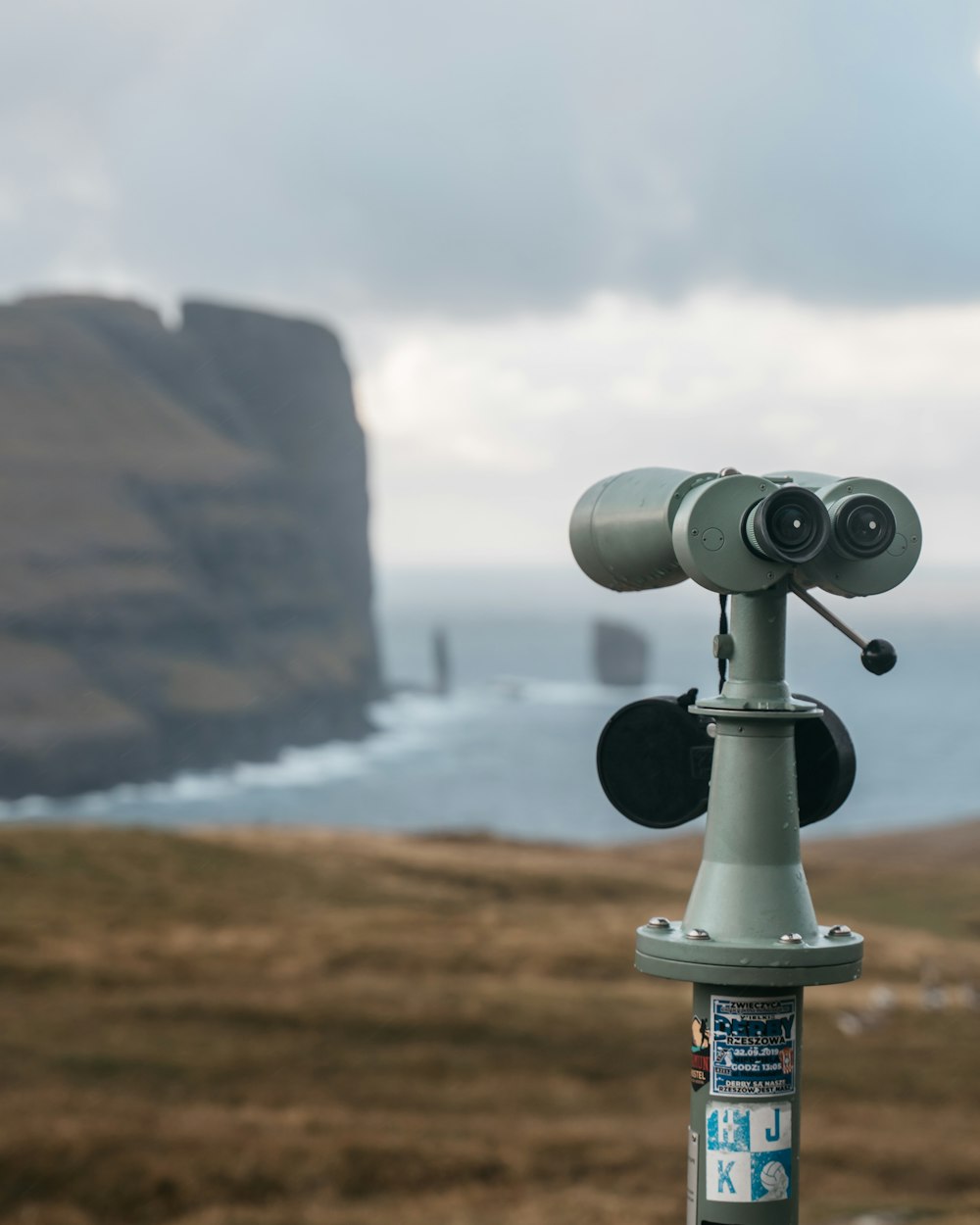 black and gray binoculars on brown rock formation near body of water during daytime