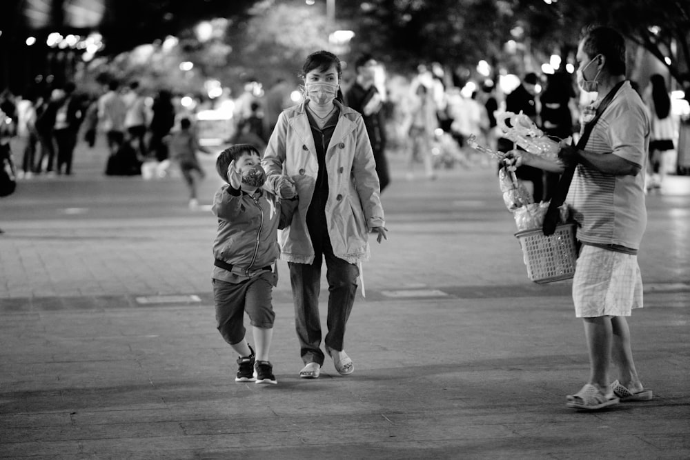 grayscale photo of man and woman walking on street