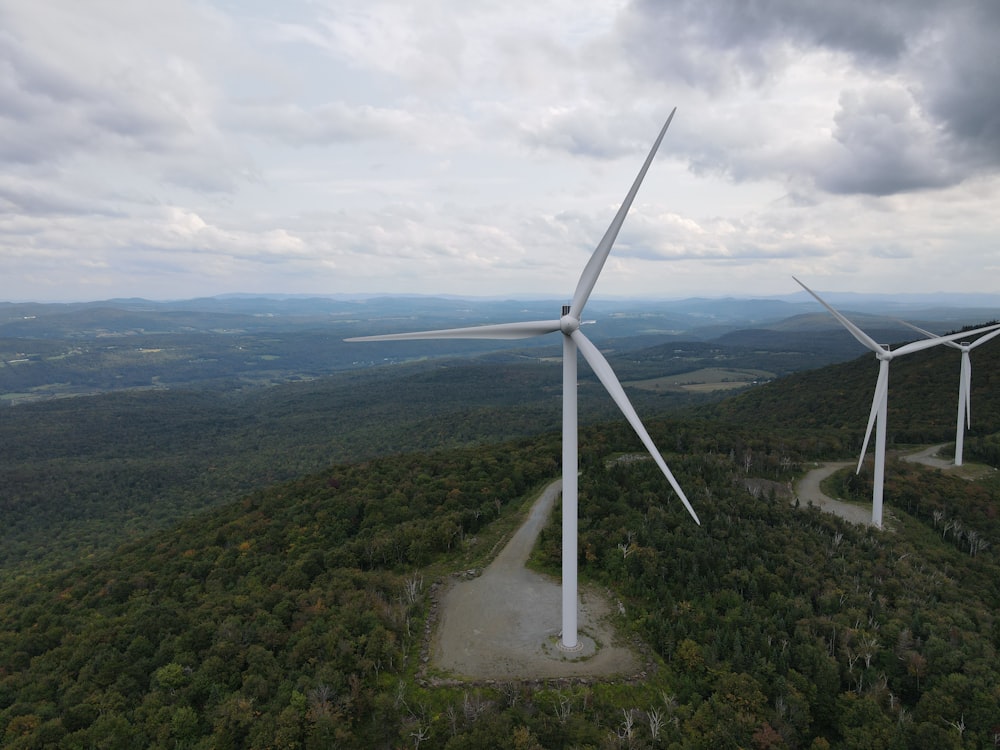 white wind turbine on green grass field under white clouds during daytime