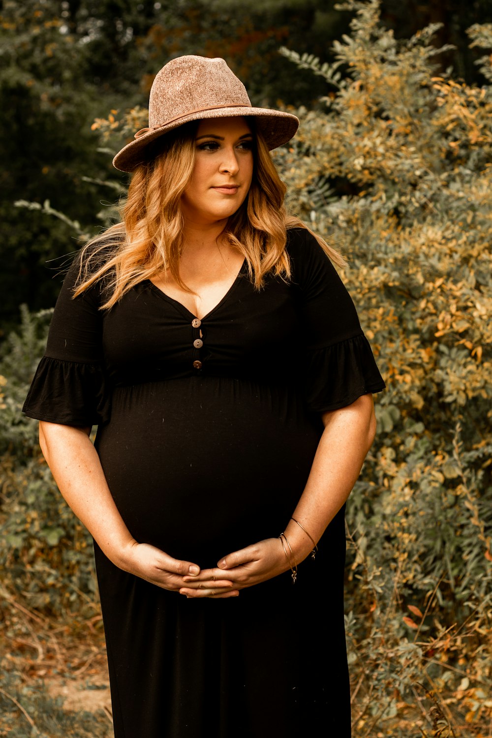 Woman in black v neck t-shirt and black fedora hat standing on white ...