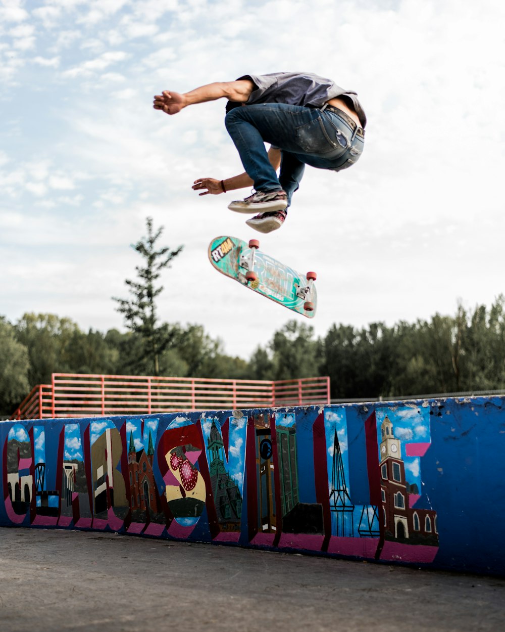 uomo in jeans blu denim e camicia nera che fa acrobazie sullo skateboard