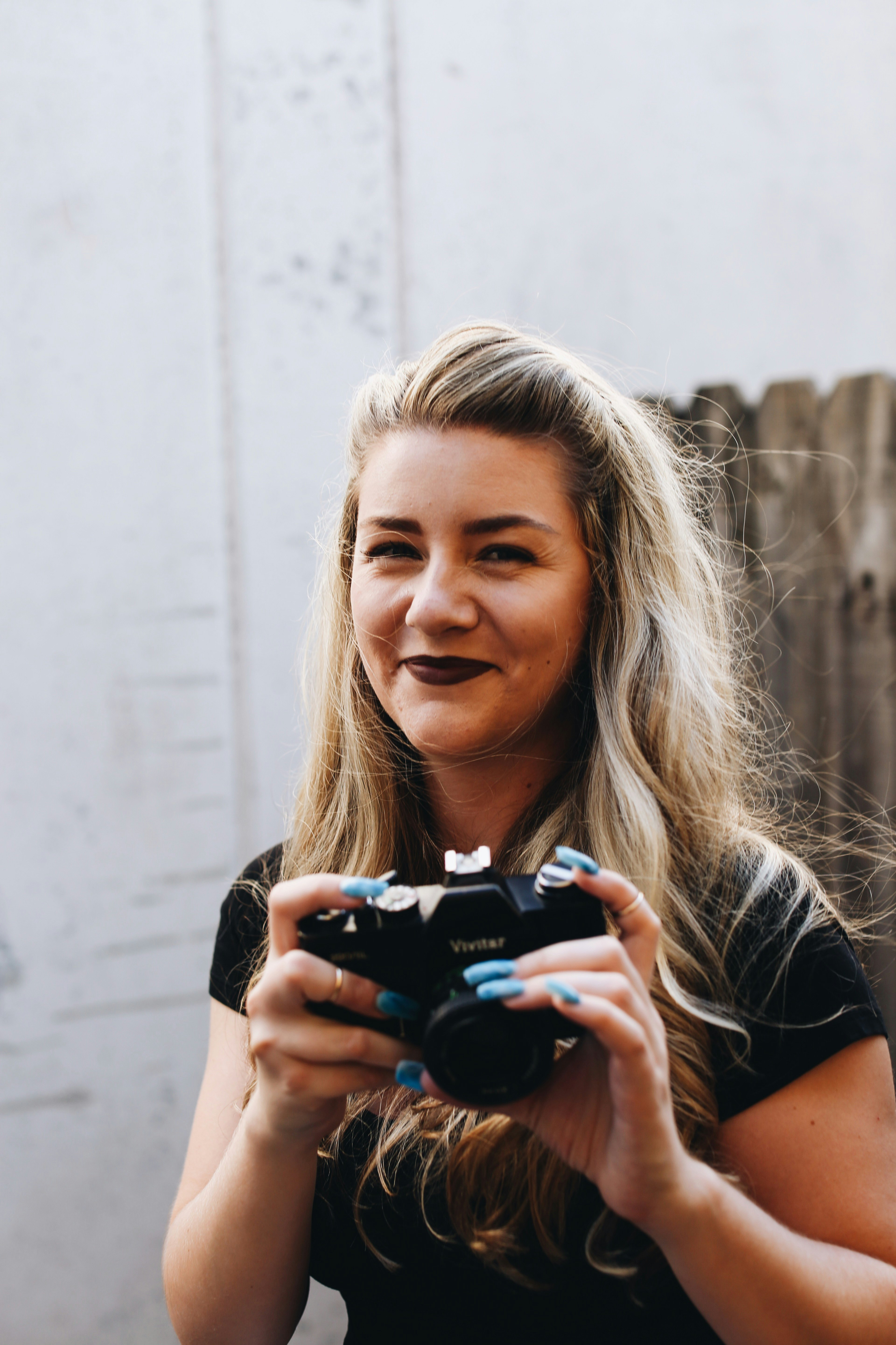 woman in black t-shirt holding black dslr camera