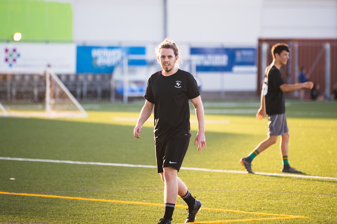 woman in black and white soccer jersey shirt running on field during daytime