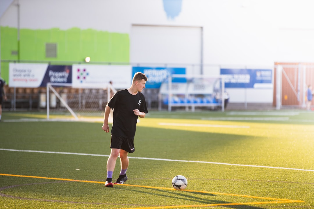 man in black shirt and shorts playing soccer during daytime