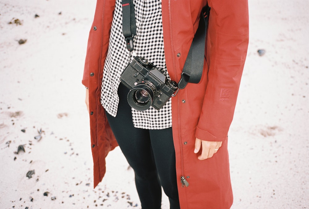 person in red blazer holding black and silver dslr camera