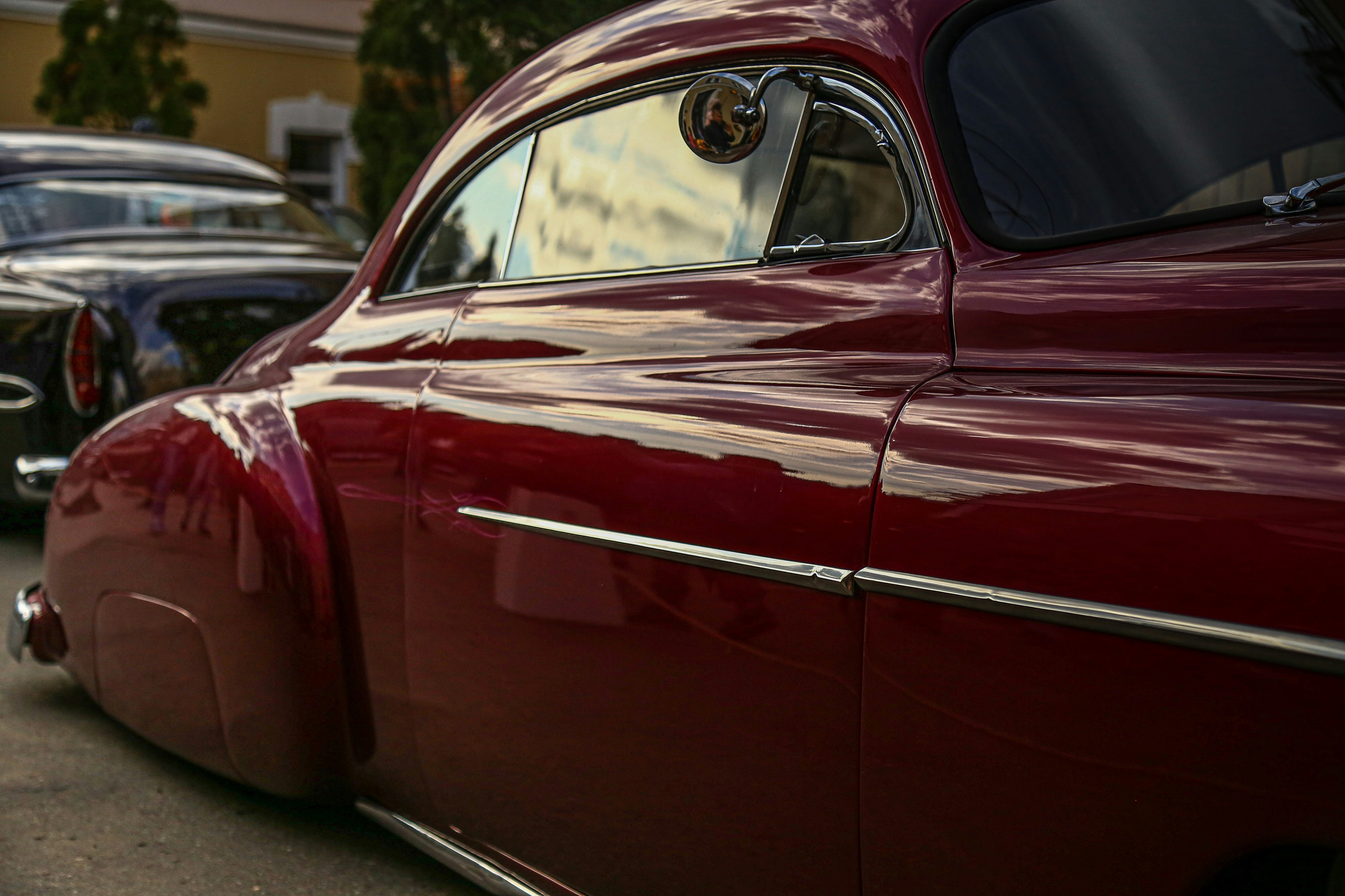 auto rossa parcheggiata sul ciglio della strada durante il giorno