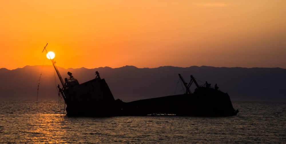 silhouette of ship on sea during sunset