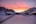snow covered houses and trees during sunset